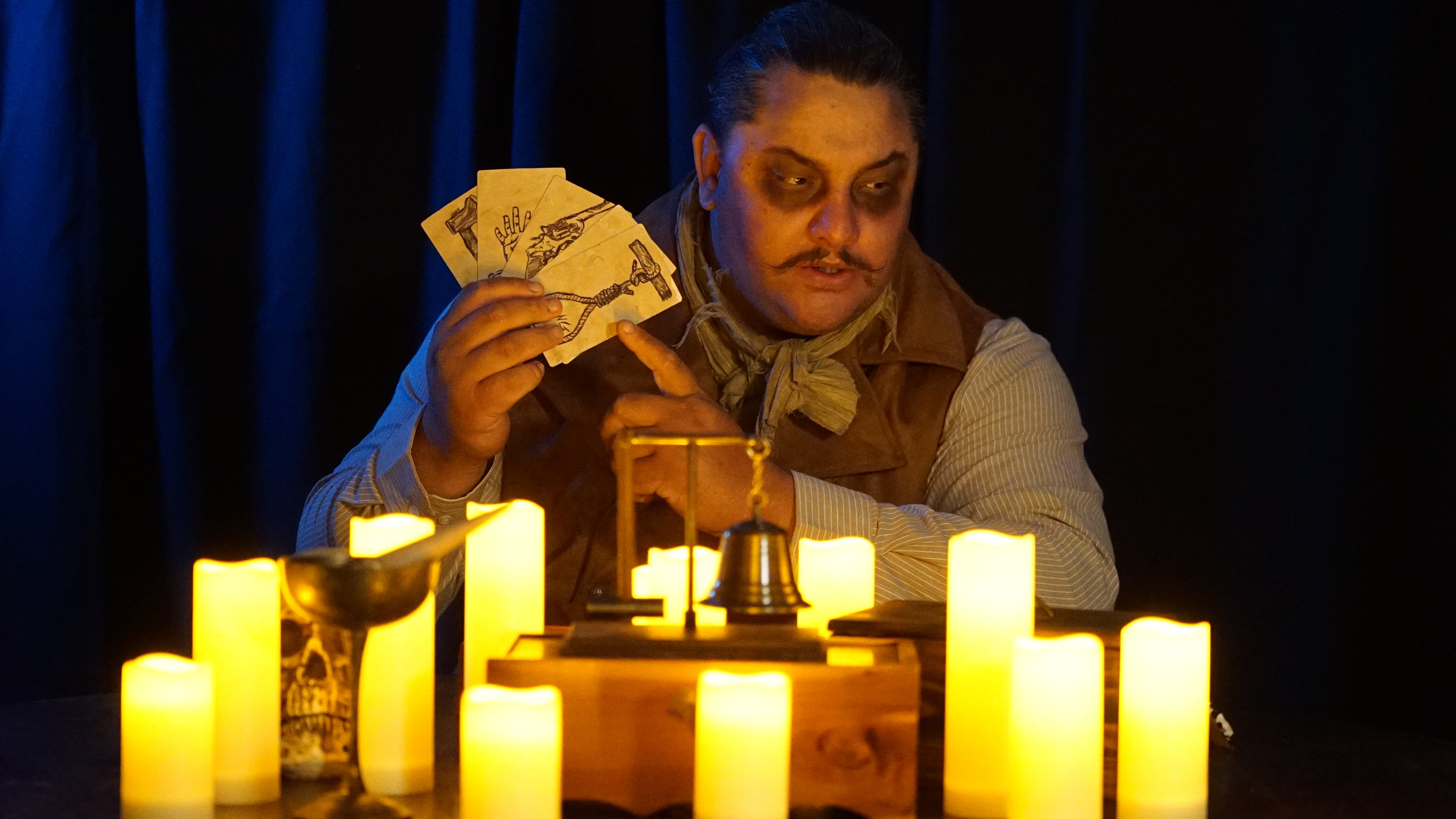 Ambrose T. Attaway reads illustrated cards at the candlelit seance table