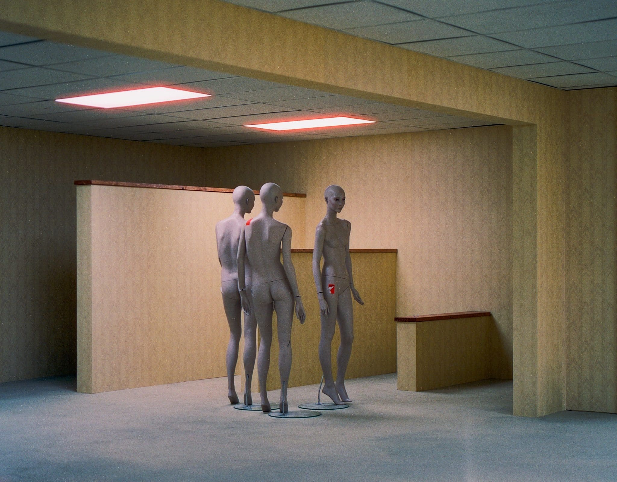 A scene from A24's Backrooms, with figures in the endless yellow rooms