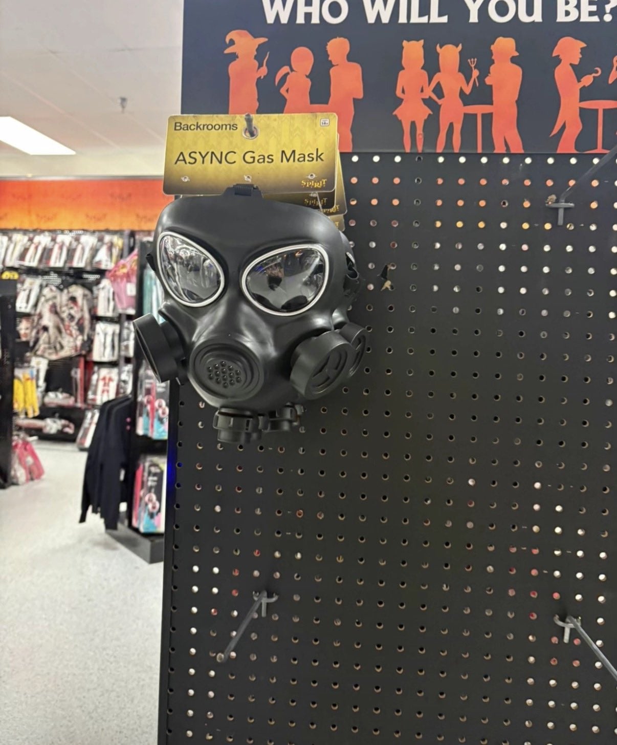 Black ASYNC Gas Mask costume hanging on a Spirit Halloween store pegboard