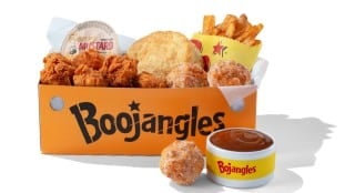 An orange Boojangles box filled with fried chicken bites, a biscuit, fries, a honey mustard cup, and sugar-coated Donut Bites, with a cup of caramel dip beside it