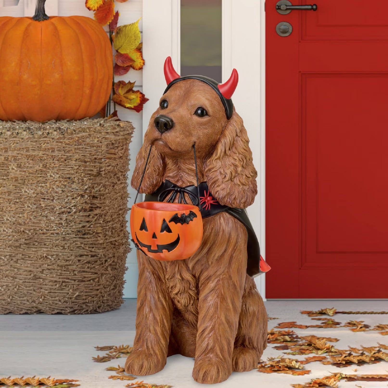 Costco 26-inch Halloween Dog Greeter, a resin dog in a devil costume holding a jack-o-lantern candy pail.