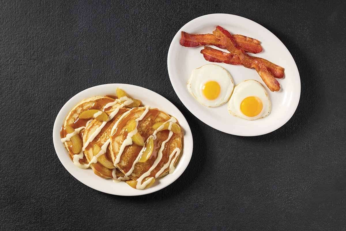 Cracker Barrel Sweet Cream Caramel Apple Pancakes with fried cinnamon apples, caramel drizzle, and vanilla cream sauce, served with eggs and bacon