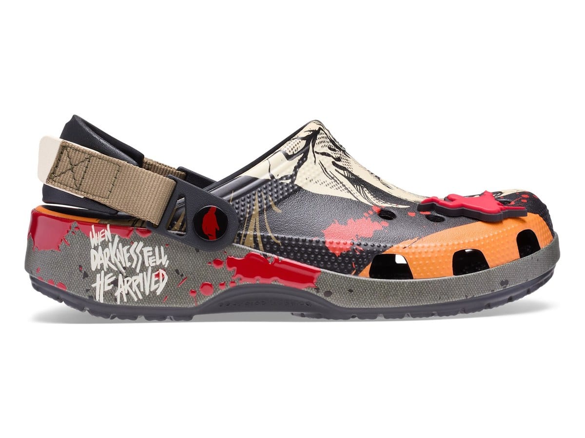Side view of the Michael Myers Classic Clog showing the khaki turbo strap and a grey midsole printed When darkness fell, he arrived