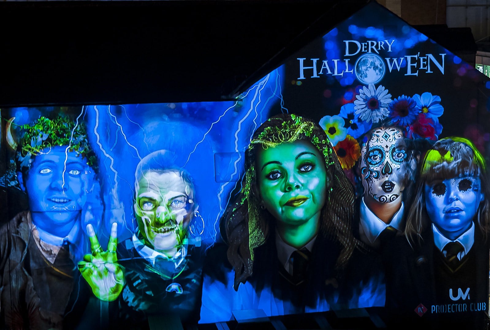 A wall mural of five figures in school uniforms with Halloween face paint under the words Derry Halloween