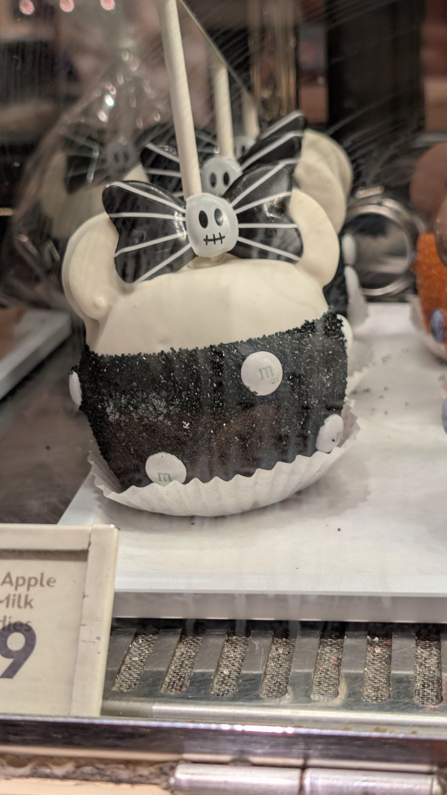 A Halloween candy apple decorated with a bow in a Disneyland display case