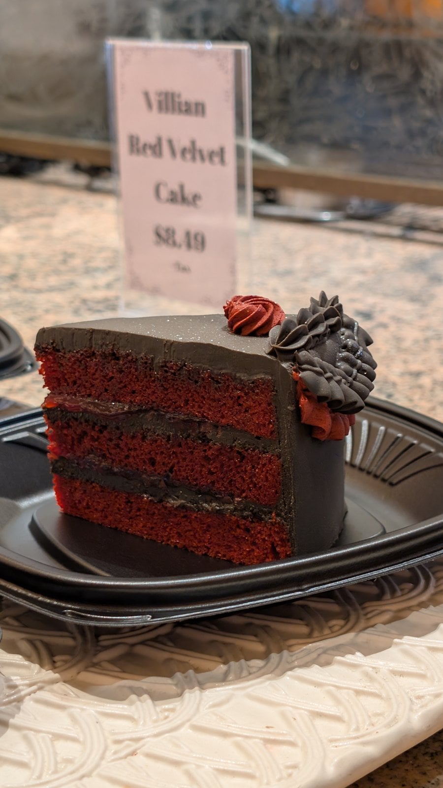 A slice of Villainous Red Velvet Cake at Plaza Inn with its $8.49 sign