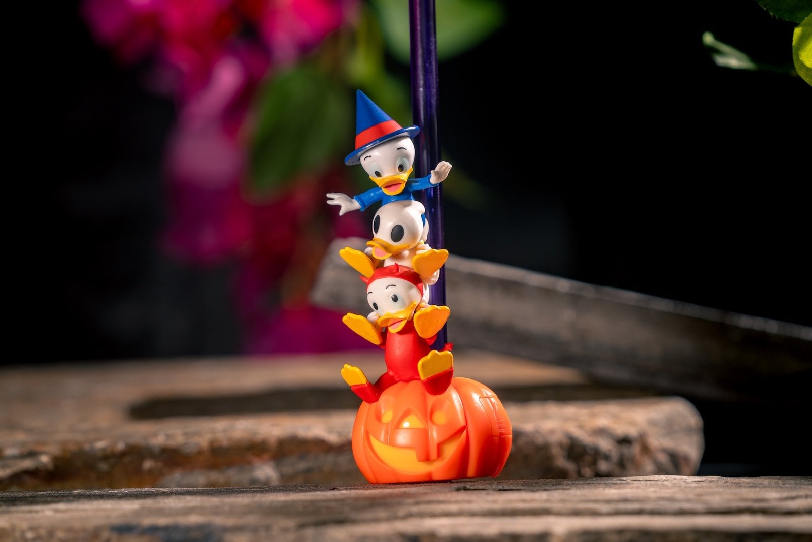 Huey, Dewey, and Louie in Halloween costumes stacked on a glowing jack-o'-lantern bottle topper