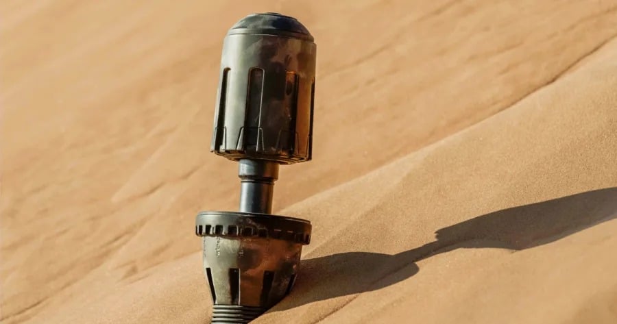 A black cylindrical device planted upright in a sand dune