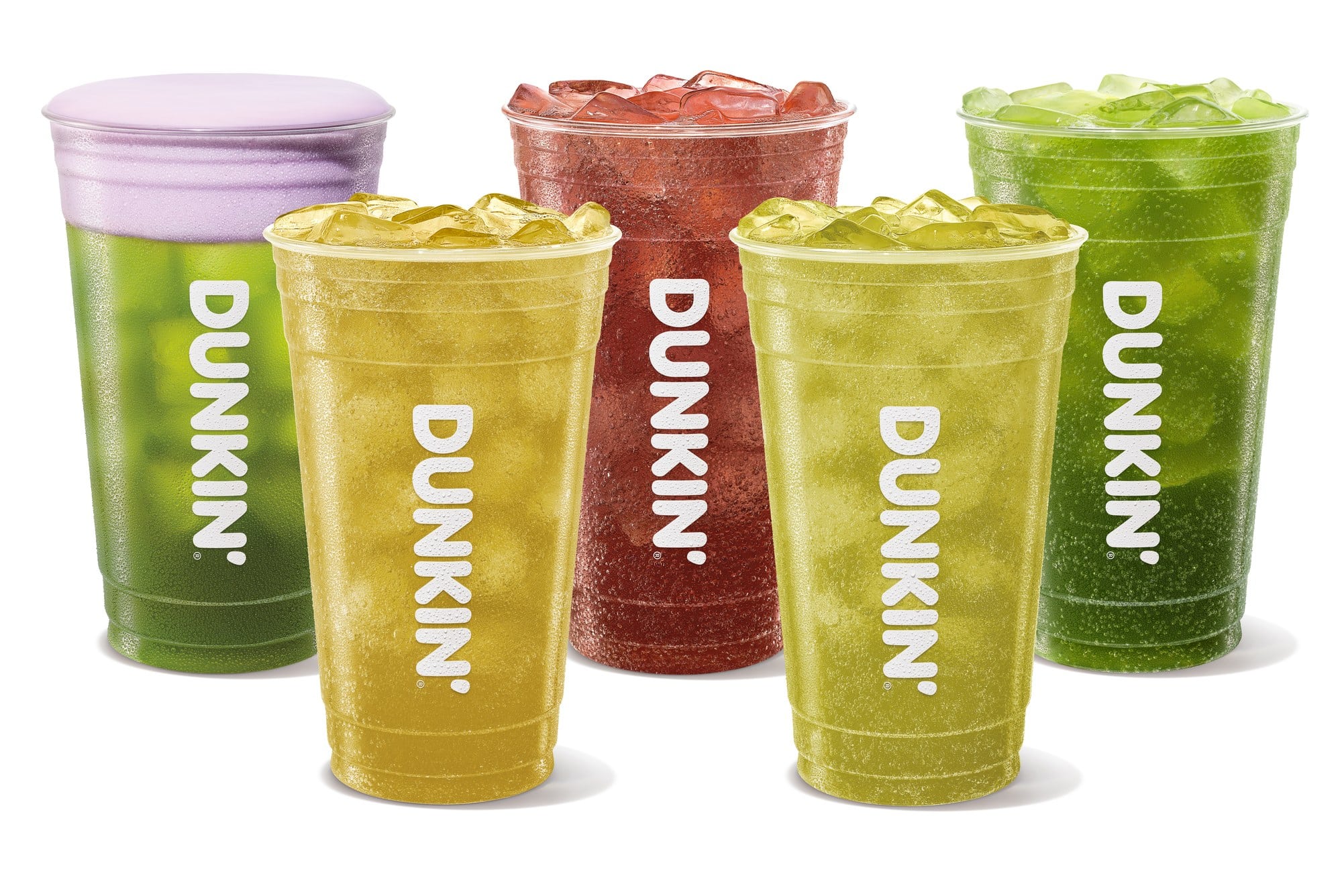 Five green, yellow, and red iced drinks in clear Dunkin cups, one topped with purple foam