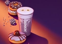 A Dunkin Spider Donut with purple frosting and a chocolate Munchkin in the center, a purple Berry Battie Daydream Refresher with candy eyes, and donuts and Munchkins with purple, chocolate, and white sprinkles