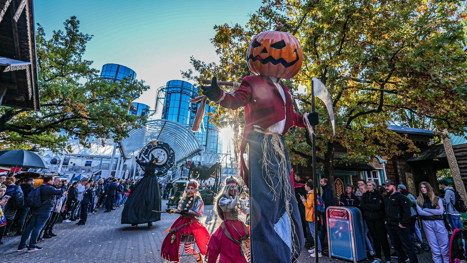 A pumpkin-headed stilt walker and costumed Halloween performers on a Europa-Park street