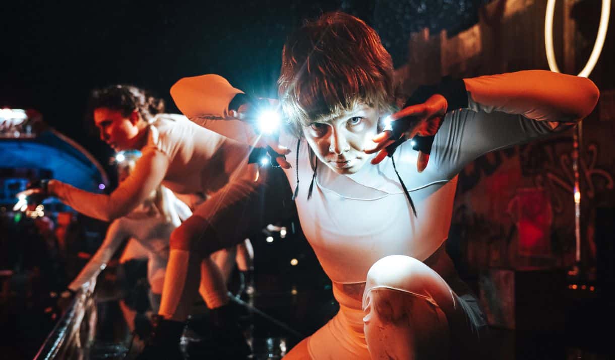 Dancers in white bodysuits with lights on their gloves perform in a dance show at FEAR Scream Park