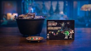 The M&M'S Amas Veritas Spell & Snack Pack for Practical Magic 2 beside a cauldron of Fun Size M&M'S bags
