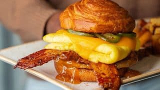 First Watch Maple Bacon Croissant Sandwich from the fall 2026 seasonal menu, with Million Dollar Bacon, egg, cheddar, and pickled jalapenos