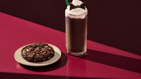 Starbucks Black Cat Frappuccino topped with chocolate cat ears beside the Venti Black Night Cookie