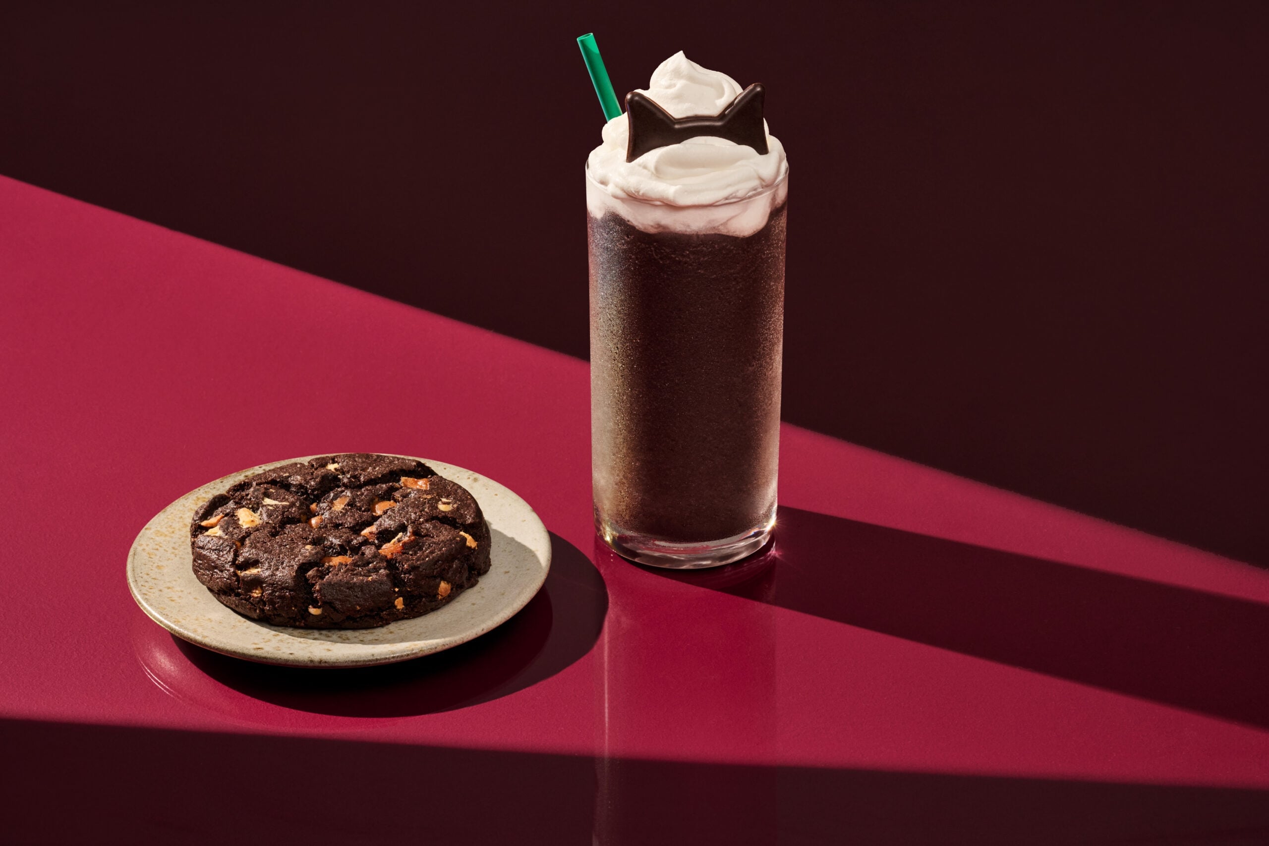 Starbucks Black Cat Frappuccino topped with chocolate cat ears beside the Venti Black Night Cookie