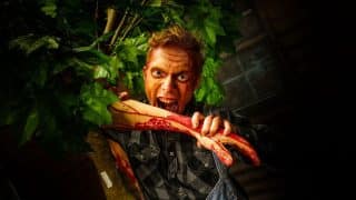 A bloodied scareactor lunges at guests during Fright Fest at Six Flags Great Adventure