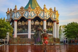 A pumpkin-headed figure and skeletons in a blood-red fountain before the carousel at Six Flags Great America Fright Fest