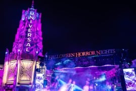 The Universal tower lit in purple beside the Halloween Horror Nights stage at night