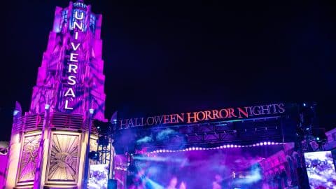 The Universal tower lit in purple beside the Halloween Horror Nights stage at night