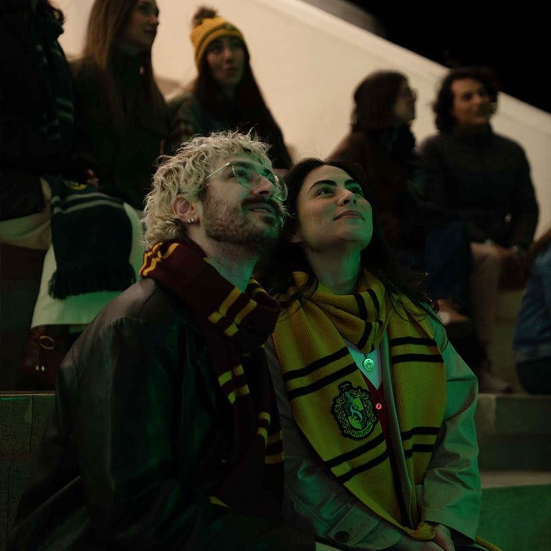 Two fans in Harry Potter house scarves watch the drone show from the stands