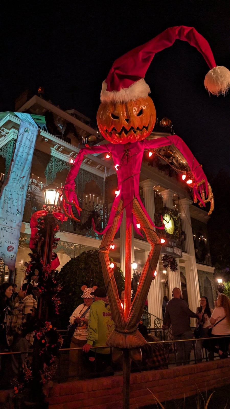A Jack Skellington pumpkin-head scarecrow outside Haunted Mansion Holiday at Disneyland at night
