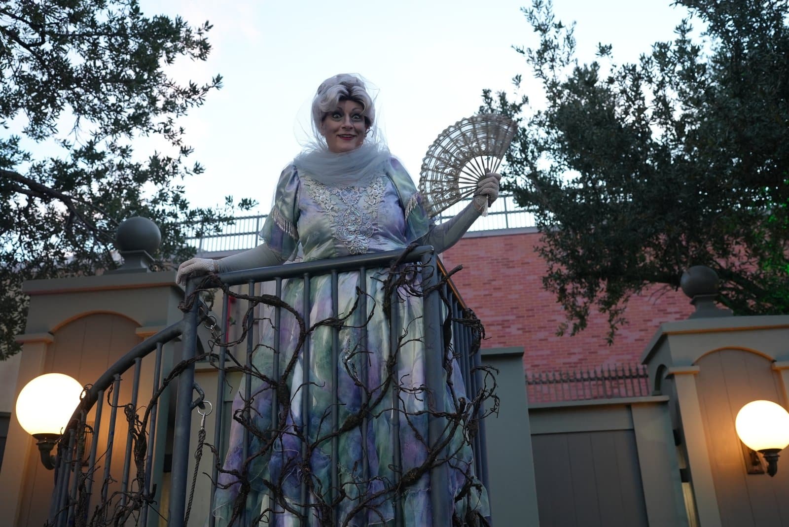 Lady Fermotta, a new Haunted Mansion character, on a vine-covered platform with a lace fan