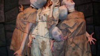 Pale, silent-screaming performers in tattered gowns bound behind barbed wire in Urban Death at Zombie Joe's Underground Theatre in North Hollywood.