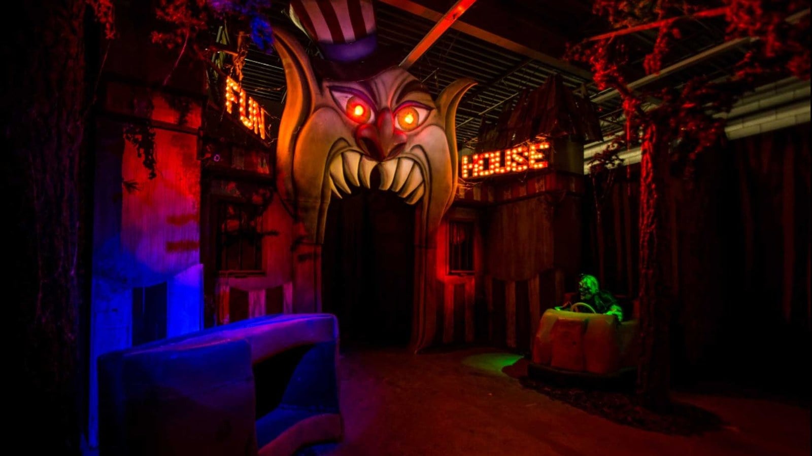 The Funhouse entrance at Reign of Terror, a fanged clown facade lit in red and blue