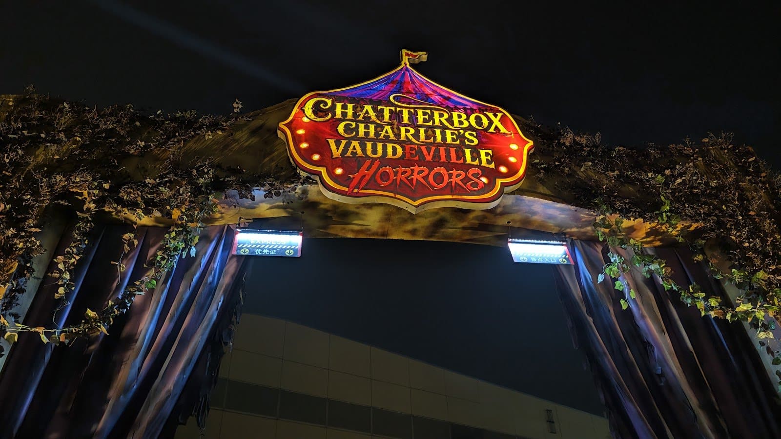A red and gold theater marquee with lit letters above a dark striped entrance at night
