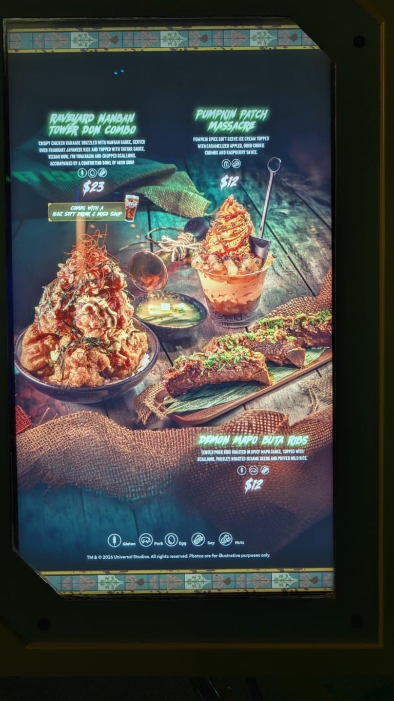 A lit menu board picturing a rice bowl with fried chicken, a soft serve dessert with a small shovel, and glazed ribs, each with a printed name and price