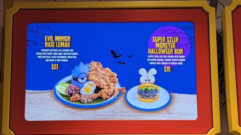 A lit menu screen picturing a plate of blue rice with fried squid and a bun with a monster face, each with a printed name and price