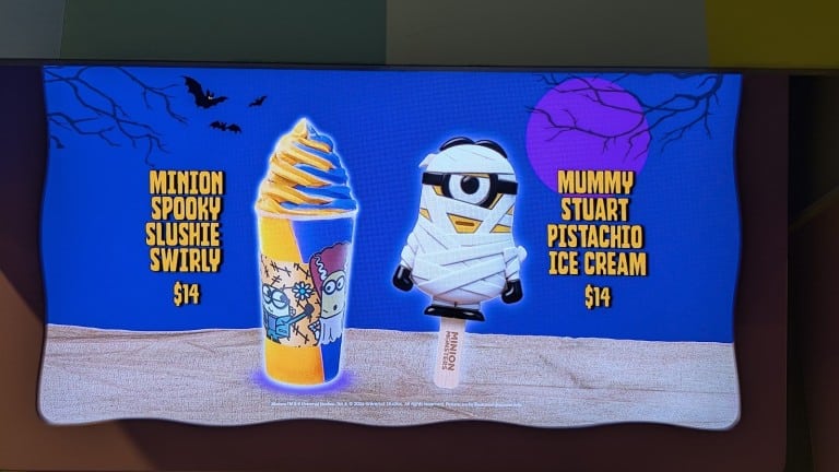 A lit menu screen picturing a swirled yellow and blue frozen drink and an ice cream bar shaped like a bandaged cartoon character, each with a printed name and price