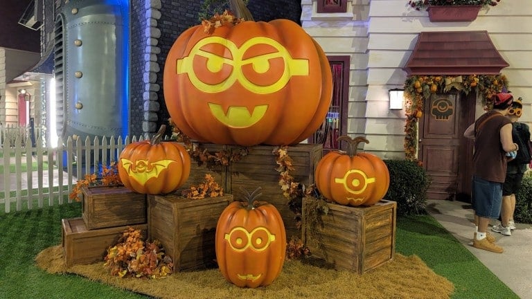 A stack of jack-o'-lanterns carved with goggle-eyed faces on crates and hay