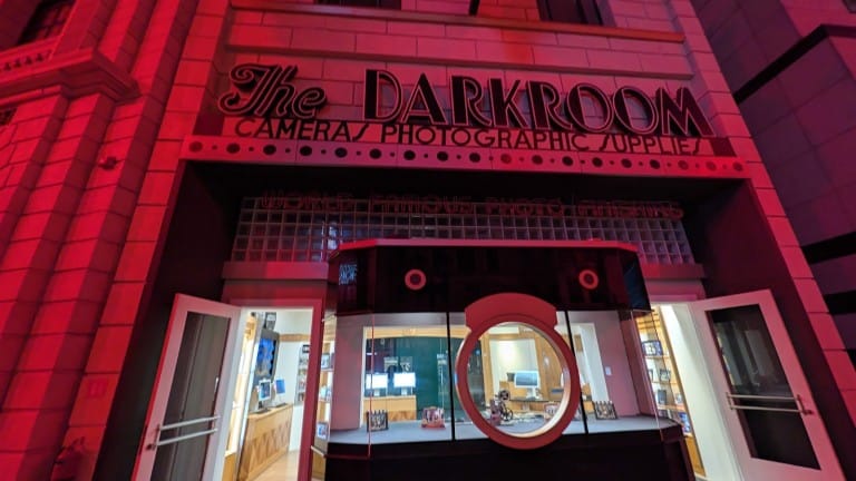 A storefront lit red with a round camera-lens window between two doors