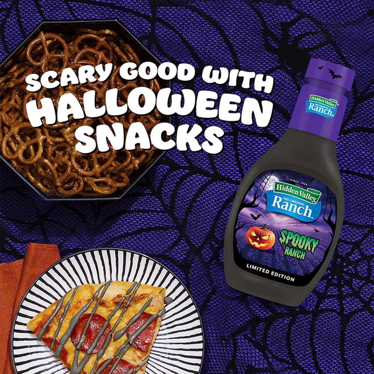 A bottle of Hidden Valley Spooky Ranch next to pretzels and a slice of pizza drizzled with black ranch