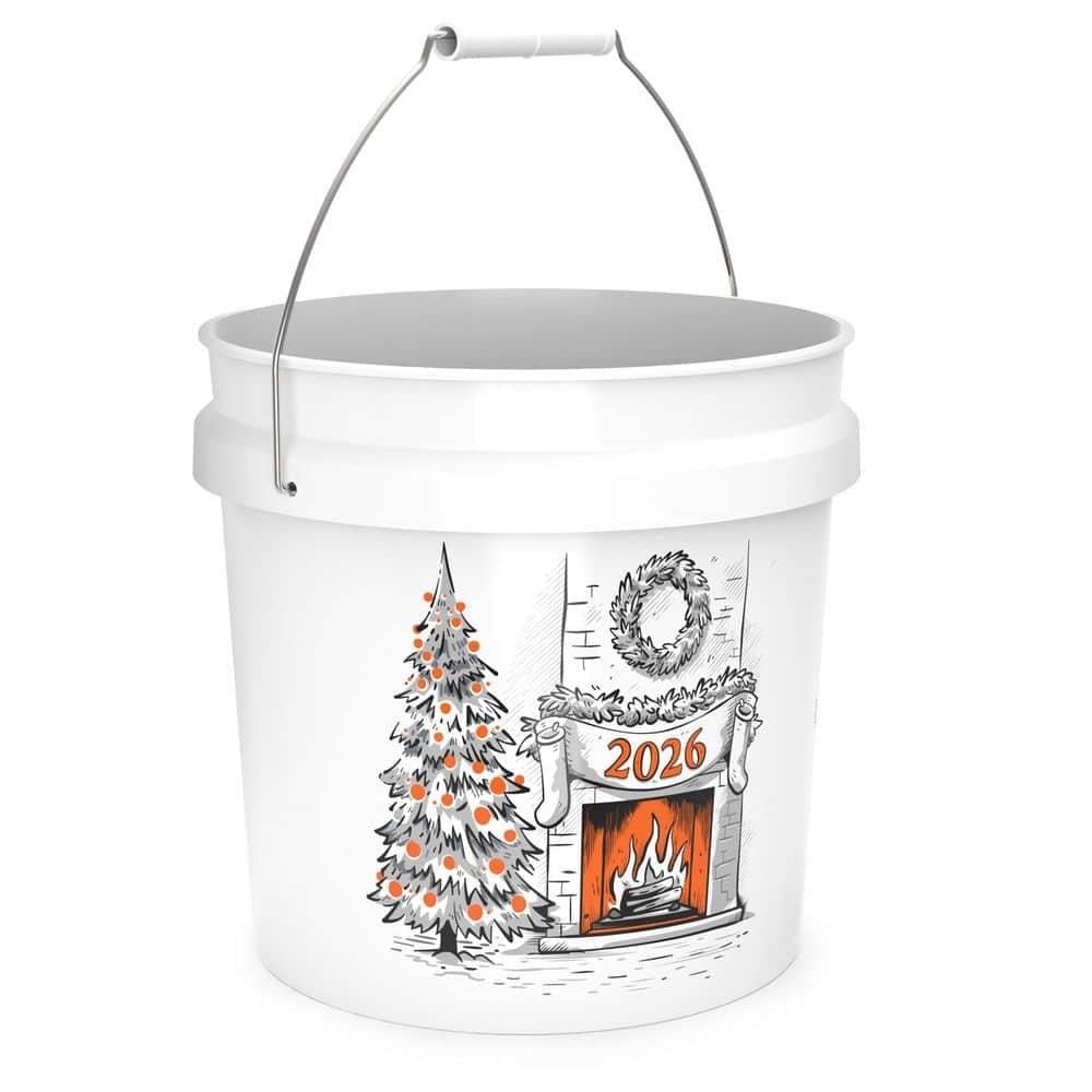 A white bucket with a metal handle, printed with a Christmas tree beside a brick fireplace with a wreath and two stockings