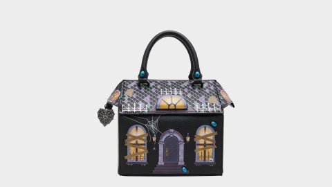 Betsey Johnson haunted house purse: a crossbody bag shaped like a spooky mansion with a tiled roof, glowing windows, and spider webs
