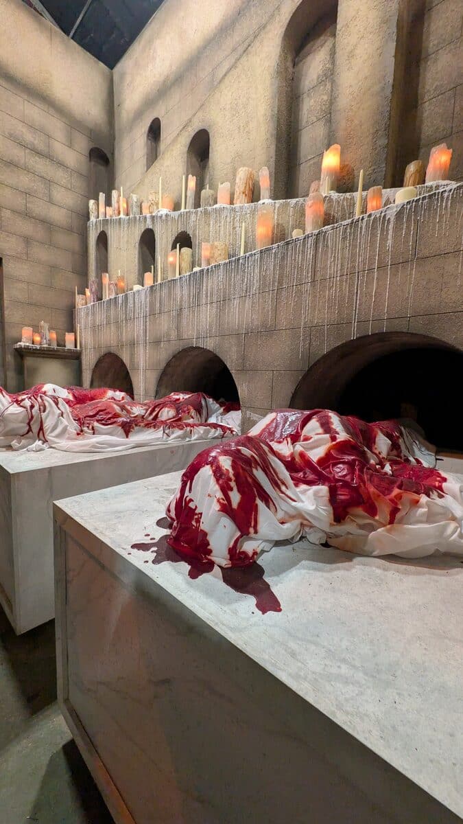 Candlelit chamber with sheeted bodies in the Hellraiser house