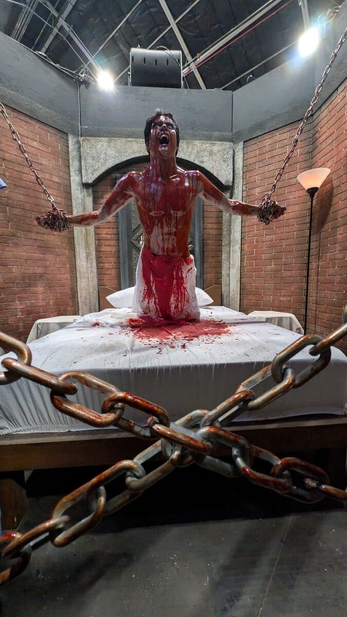 Blood-drenched figure chained on a mattress in the Hellraiser house