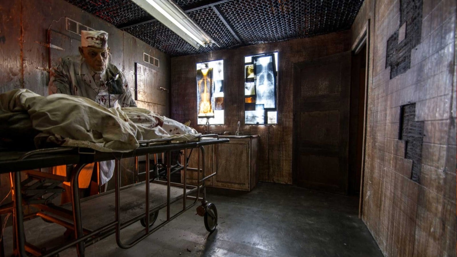 An asylum operating-room set with a bloodied figure over a gurney at Reign of Terror