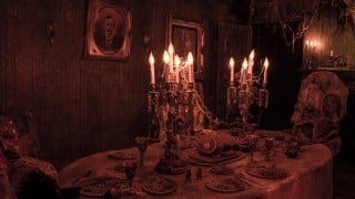 A cobwebbed Victorian dining room set with a seated skeleton at Reign of Terror Haunted House