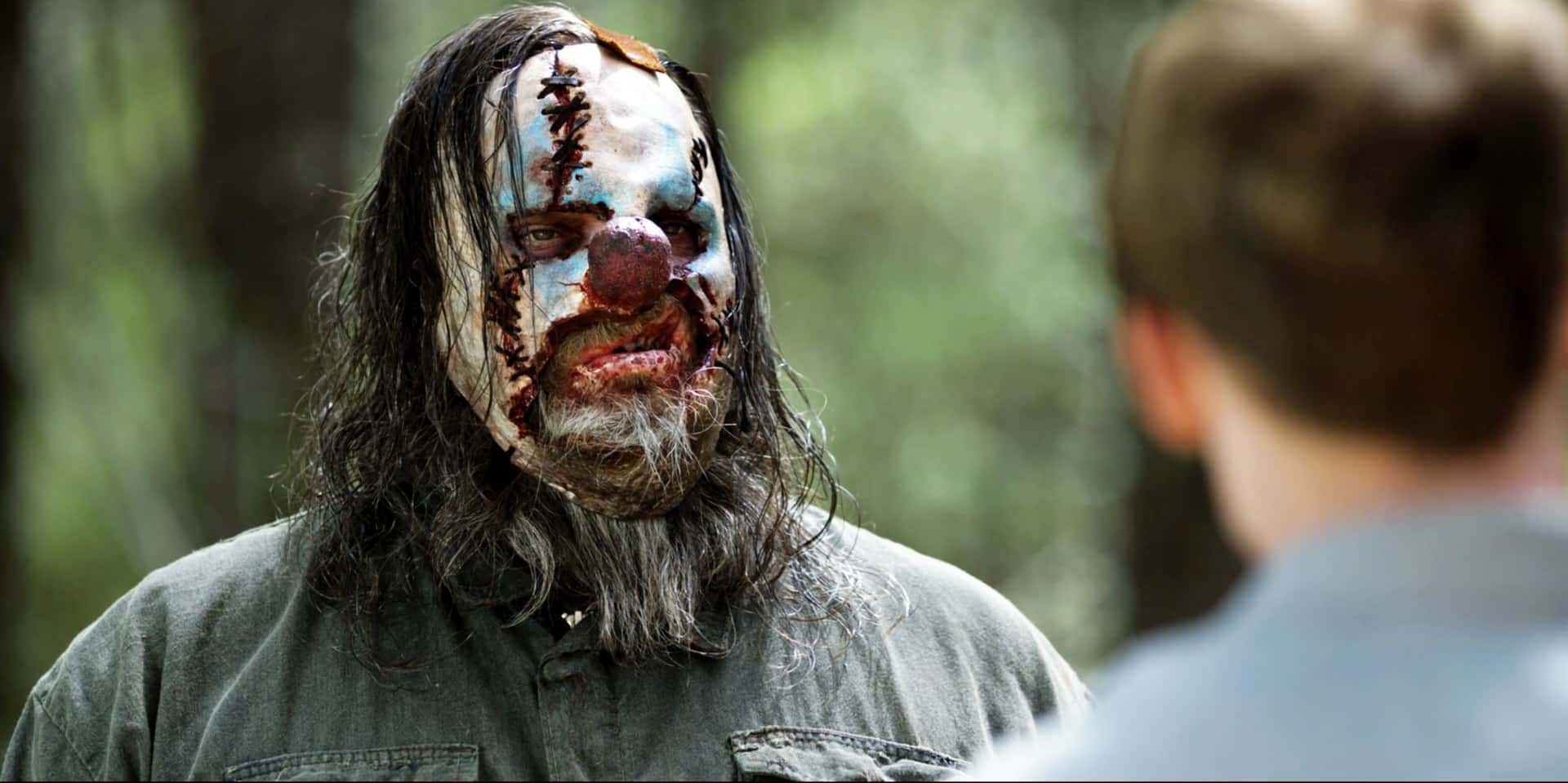Tickles, a clown with a stitched face and long gray hair, in a scene from Hellbilly Hollow