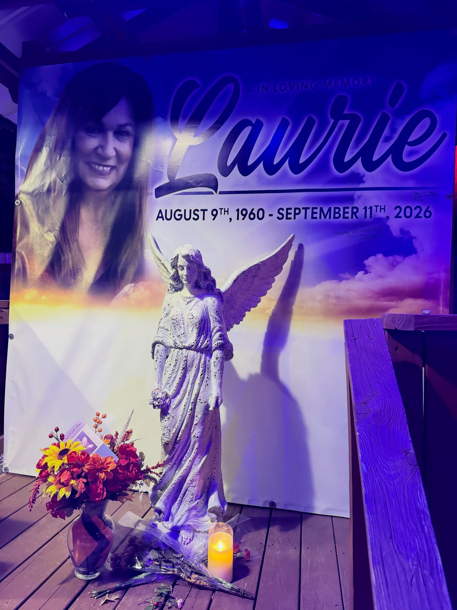 Laurie's memorial on the Woods of Terror Midway, with a banner, an angel statue, autumn flowers, and a candle