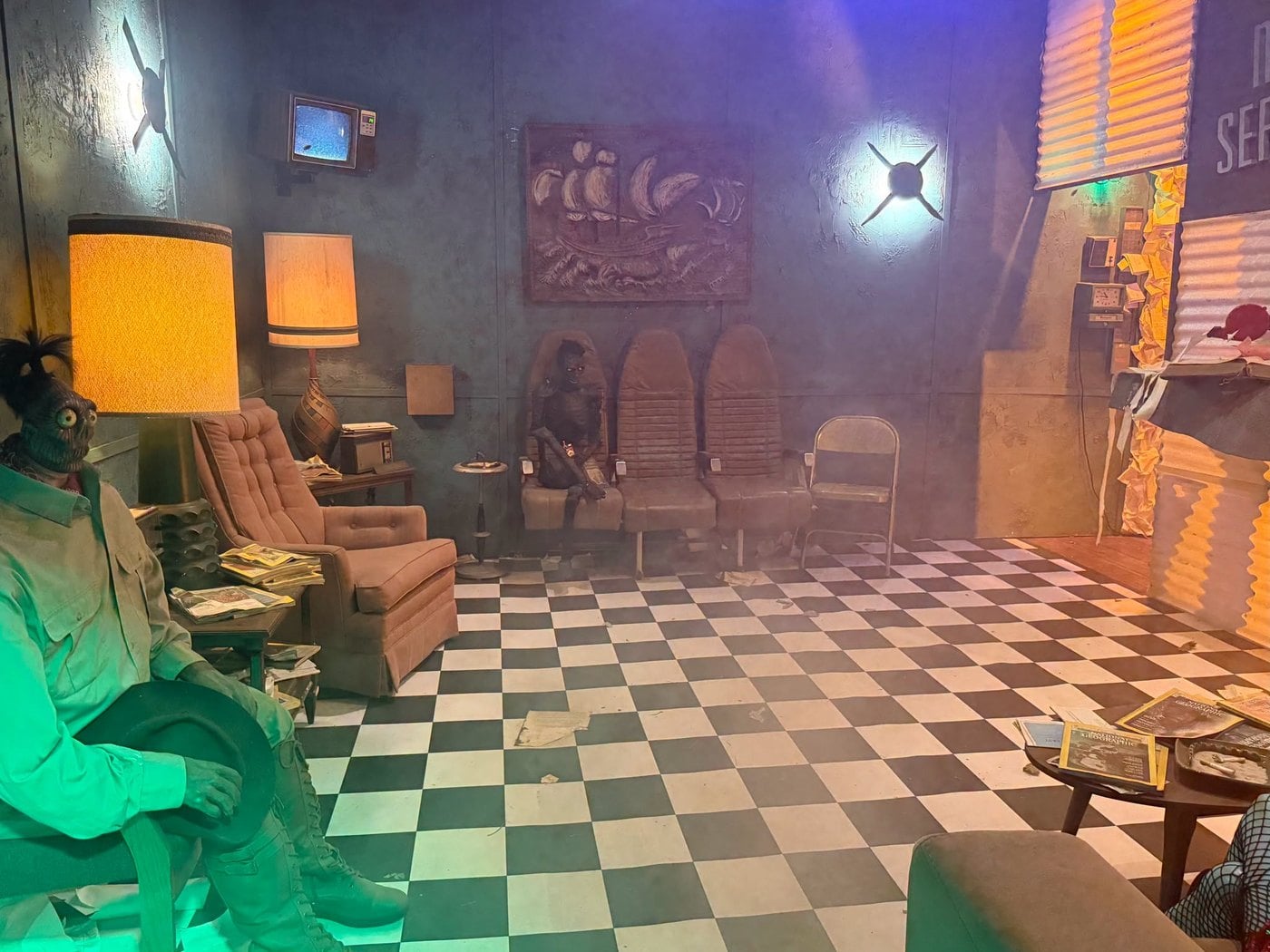 The Afterlife waiting room set at The Lucky Rabbit, with a checkered floor, lamps, armchairs, and seated dead figures