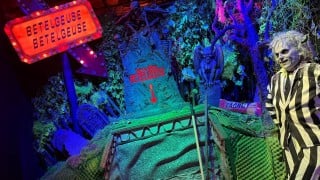 A Betelgeuse Betelgeuse marquee sign pointing at a here lies Betelgeuse tombstone, with a Beetlejuice figure in a striped suit, at The Lucky Rabbit in Hattiesburg