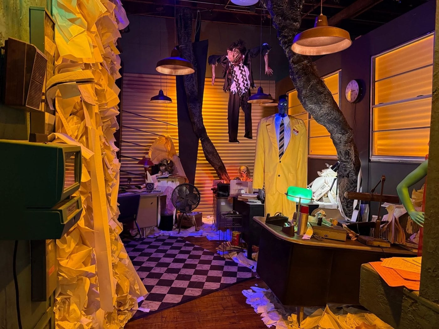 A caseworker office buried in paper, with desk lamps, a yellow suit, and a hanging figure, in The Lucky Rabbit's Beetlejuice walkthrough