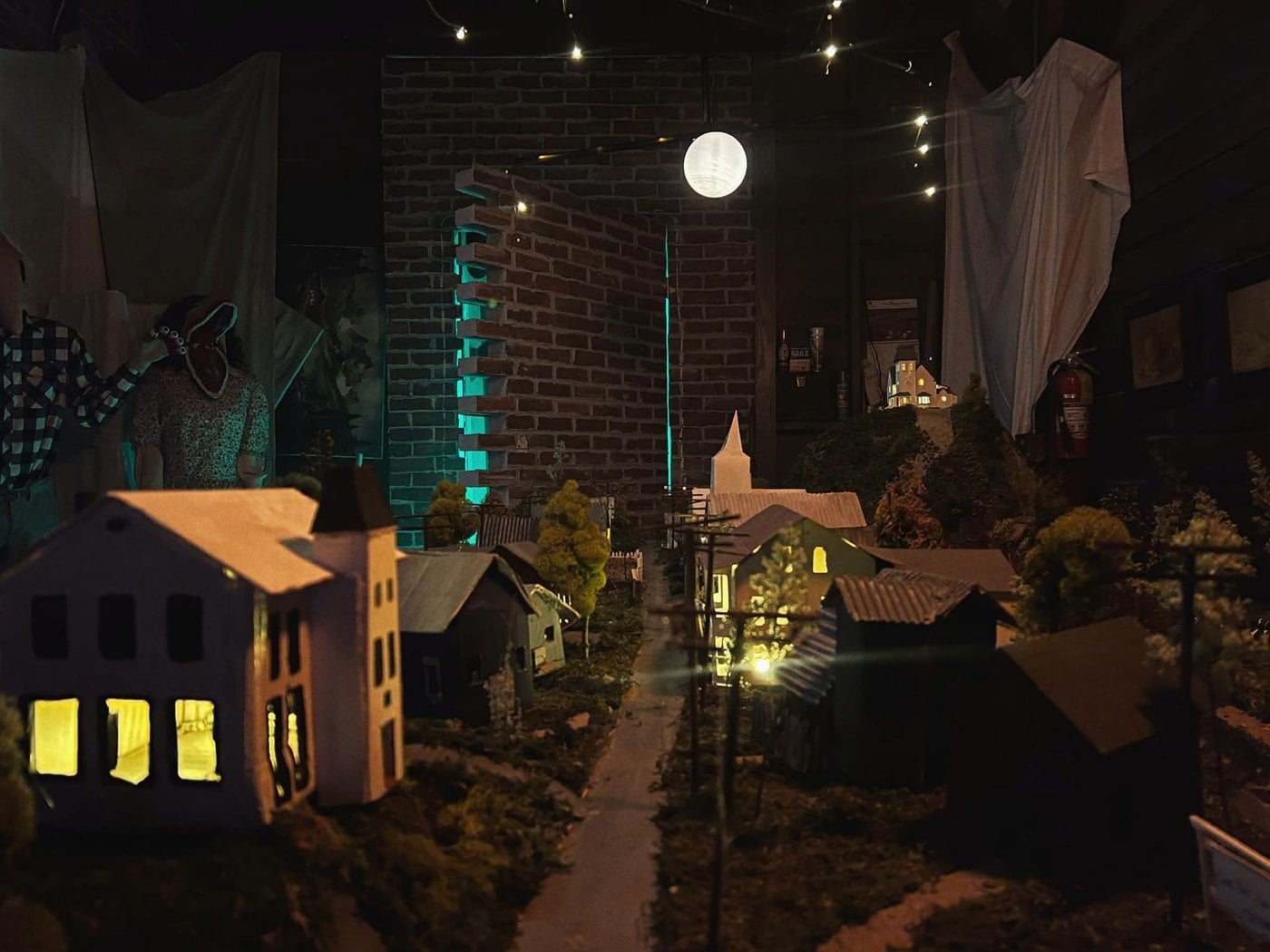 A miniature model town of lit white houses and a church under a moon in The Lucky Rabbit's Beetlejuice walkthrough