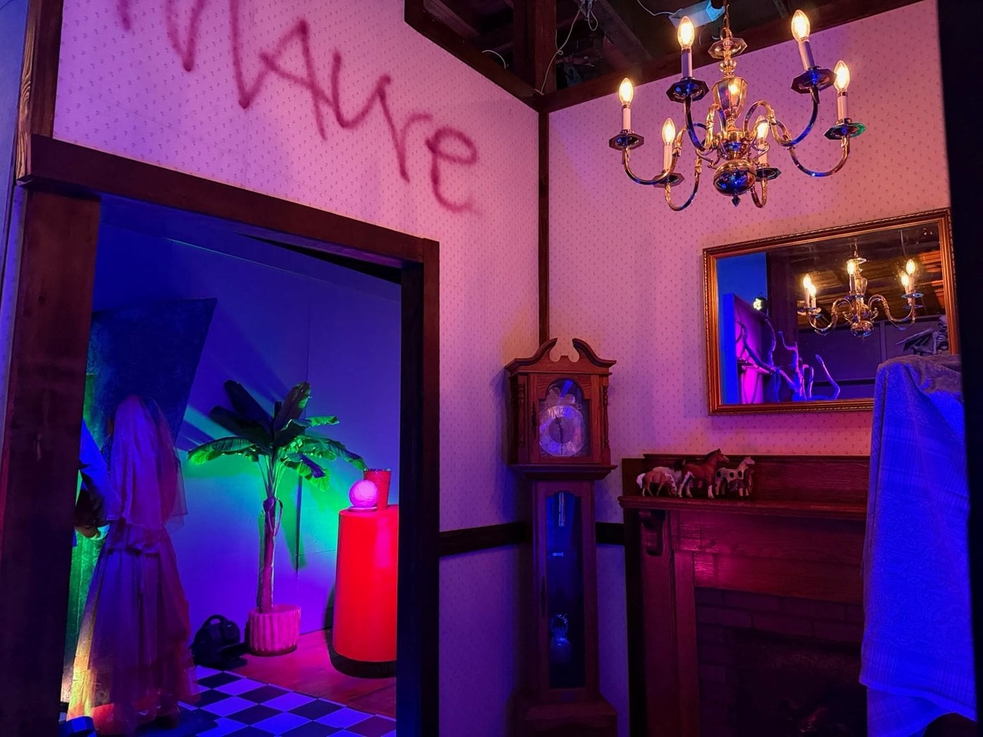 A pink parlor set with a chandelier, a grandfather clock, a mirror, and a spray-painted wall at The Lucky Rabbit