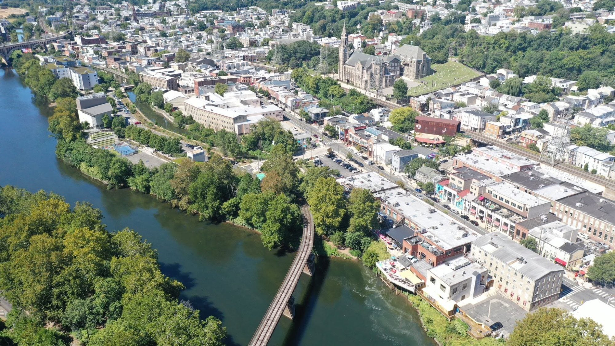 Manayunk from the air: the Schuylkill River, the canal, a footbridge and the neighborhood's brick buildings on the hillside